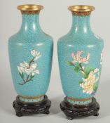 A GOOD PAIR OF CHINESE BLUE GROUND CLOISONNE VASES, on wooden stands, each decorated with flora,