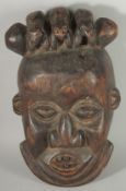 AN AFRICAN CARVED WOOD TRIBAL MASK, the head with three toads, 26cm x 22cm.