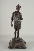 A LARGE INDIAN CARVED HARDWOOD FIGURE, of a man holding a parasol with bone finial, raised and