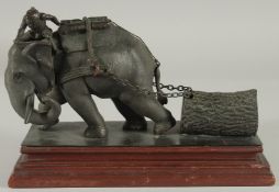A FINE INDIAN BRONZE FIGURE OF AN ELEPHANT, pulling a tree trunk on chains with a man seated atop,
