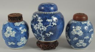 THREE CHINESE BLUE AND WHITE PRUNUS JARS AND COVERS, two with wooden covers and one with wooden