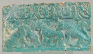 A 12TH CENTURY PERSIAN KASHAN TURQUOISE GLAZED POTTERY TILE, with relief felines, 35.5cm x 19.5cm.