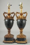 A PAIR OF TALL FAUX MARBLE AND GILT URN SHAPED LAMPS on pedestal bases. 28ins high.