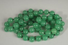 A STRING OF JADE BEADS 28ins long.