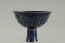 A CHINESE DARK BLUE STEM CUP the sides with a dragon. 5.5ins diameter.