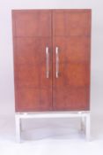 A TAN LEATHER AND CHROME BAR CABINET with double panel doors 5ft 4ins high, 3ft wide, 1ft 4ins