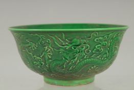 A CHINESE GREEN PORCELAIN CIRCULAR BOWL the sides with dragons. Mark in blue. 6ins diameter.