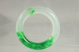 A PLAIN TWO TONE JADE BANGLE. 3.5ins diameter.