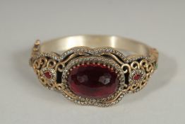 A SILVER AND GILT RUBY AND EMERALD BANGLE.