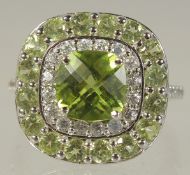 A 9CT WHITE GOLD DIAMOND AND PERIDOT RING.