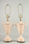 A PAIR OF PINK PORCELAIN TWO HANDLED URN SHAPED VASE LAMPS. 15ins high.