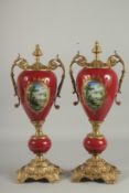 A GOOD PAIR OF BRONZE AND PORCELAIN RED FLORAL TWO HANDLED URNS. 18ins high.