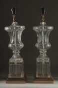 A GOOD PAIR OF GLASS URN SHAPED LAMPS on square bases. 27ins high.