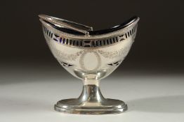 A VICTORIAN BRIGHT CUT AND PIERCED BOAT SHAPED SUGAR BASKET with sapphire blue liner. London 1893.
