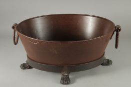 AN OVAL METAL PLANTER with ring handles on four claw feet. 20ins wide.