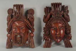 A LARGE PAIR OF CHINESE CARVED HARDWOOD MASKS. 14ins long.