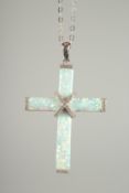 A SILVER OPAL SET CROSS on a chain.