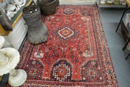 A Persian carpet, red ground with stylised decoration (moth damage) 245cm x 160cm.