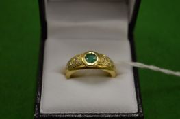 An 18ct gold ring set with a single central emerald flanked by diamonds to the shoulders size Q.