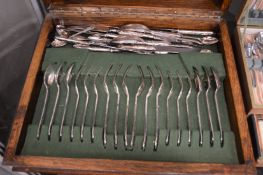 An oak cutlery canteen containing various plated flatware.