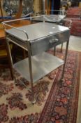 A stainless steel two tier single drawer trolley.