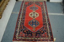 A good small Persian design rug, crimson ground with three central large motifs 185cm x 110cm.