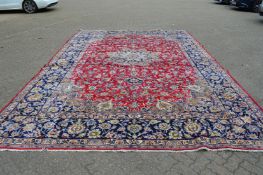 A good large Persian design carpet, red ground with floral decoration within a blue ground border