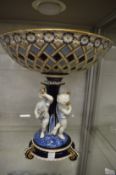 A Continental porcelain centrepiece modelled as a lattice bowl supported on a column with three