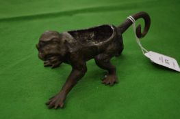 A cast metal monkey, possibly a base of a pen wipe or pin cushion.