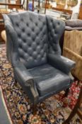 A George III style blue leather upholstered wing armchair.