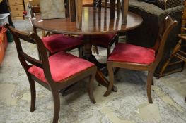 A mahogany circular pedestal dining table and four chairs.