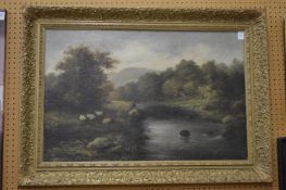 Wooded river landscape with resting sheep, oil on canvas in a decorative gilt frame.