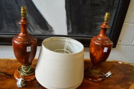 A pair of vase shaped turned wood table lamps with shades.