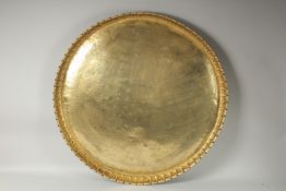 A VERY LARGE ISLAMIC BRASS TRAY, with panels of calligraphy, 73.5cm diameter.
