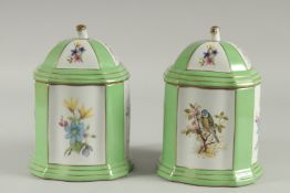 A PAIR OF SEVRES DESIGN GREEN LIDDED CANNISTERS with panels birds and flowers. 8 ins high.
