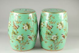 A PAIR OF GREEN PORCELAIN BARREL SEATS painted with birds. 18ins high.