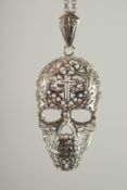 A SILVER FILIGREE SKULL PENDANT AND CHAIN.