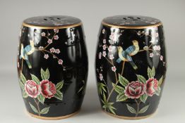 A PAIR OF FAMILLE NOIRE PORCELAIN BARREL SEATS painted with birds. 18ins high.