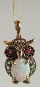 A 9CT GOLD OPAL, RUBY AND EMERALD OWL PENDANT AND CHAIN.