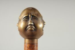 A WALKING STICK with bronze Buddha handle.