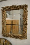 A naturalistically framed rectangular wall mirror.