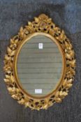 A decorative oval wall mirror with floral frame.