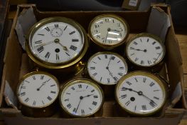 A brass ships clock and six similar brass circular bedside/mantle clocks.