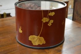 A Japanese circular lacquer container housing dry flower arrangement.