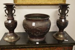 A Japanese cast metal jardiniere and a pair of similar vases with later bases.