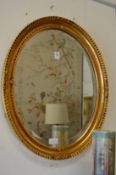A modern gilt framed oval wall mirror.