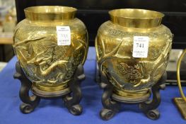 A pair of Chinese brass vases on stands.