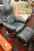 A green leather upholstered reclining swivel armchair with matching foot stool.