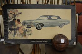 An old leather football and an advertising card for a Chevrolet Impala Sport Coupe.