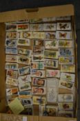 A large collection of cigarette cards, some contained in an album.